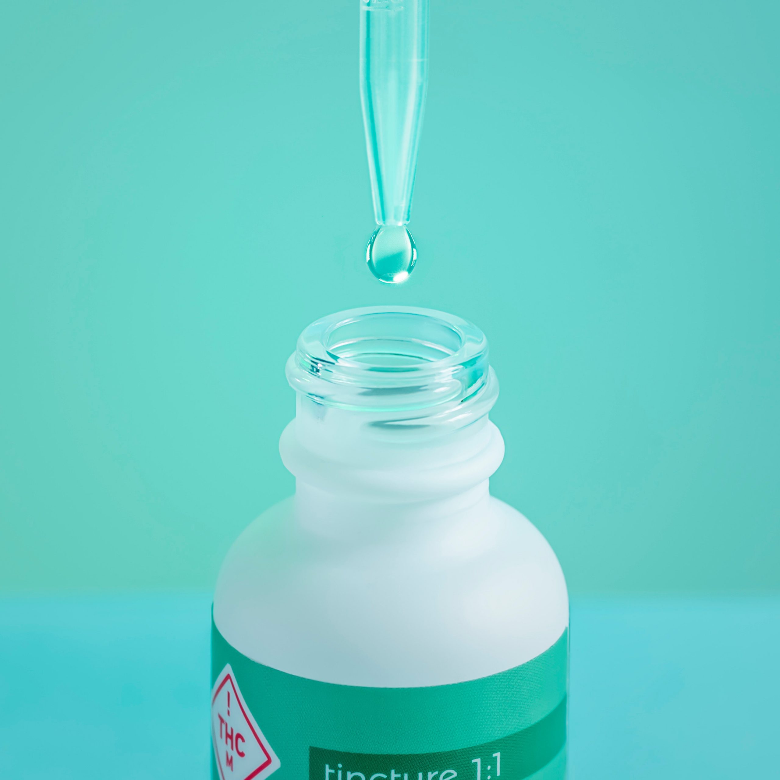 CBD oil dropper bottle with drop falling into the bottle.